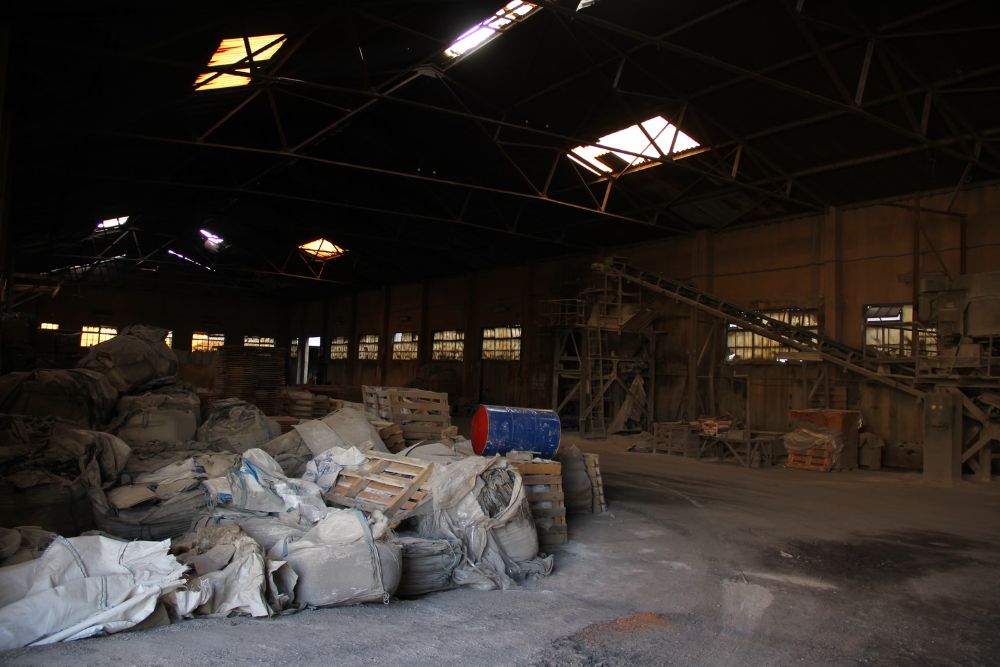 A vast warehouse containing multiple rubble piles, representing a bulk junk removal service based in San Antonio, TX.