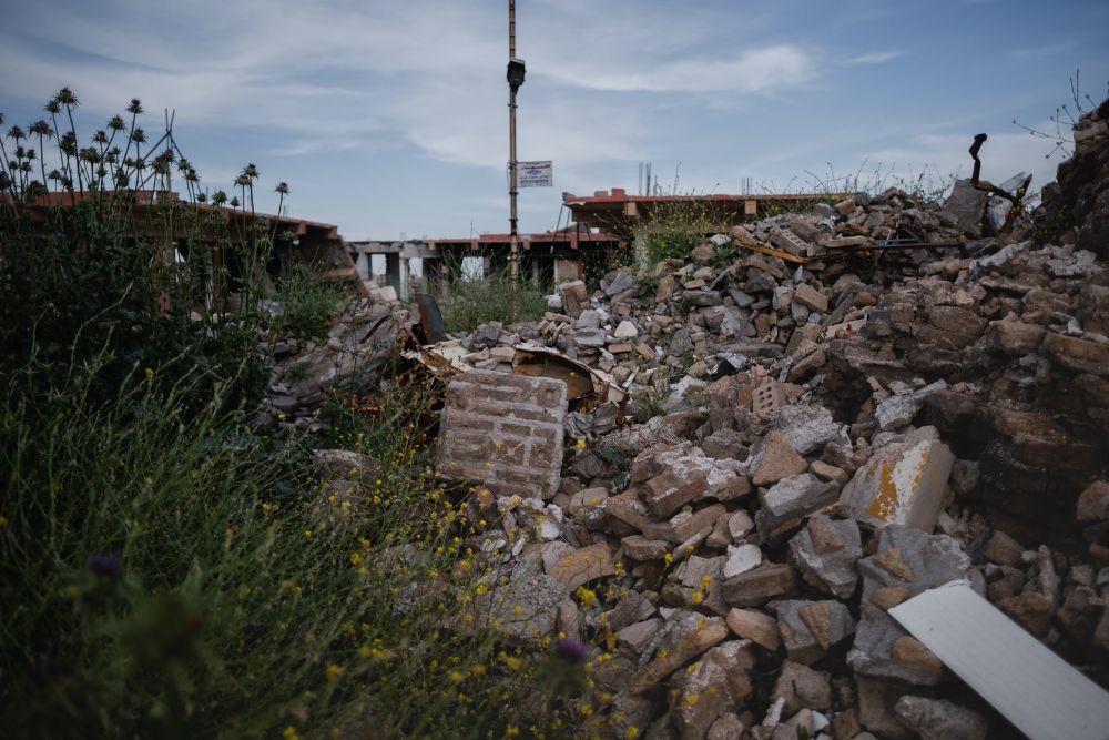 A building is surrounded by a pile of rubble and weeds, showcasing construction and renovation work in San Antonio, TX.